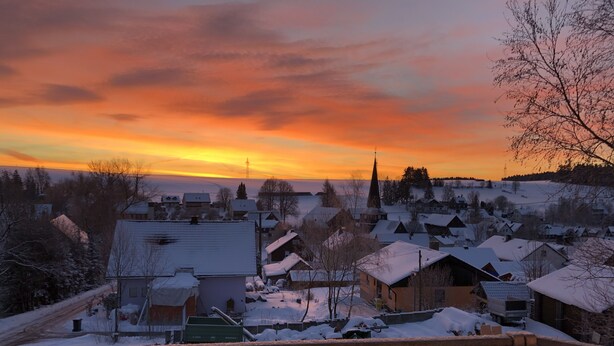 Un village enneigé avec des maisons et une église, vu depuis un balcon.