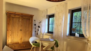 Une pièce avec une armoire en bois, une table blanche avec des chaises, un radiateur et une fenêtre avec des rideaux.