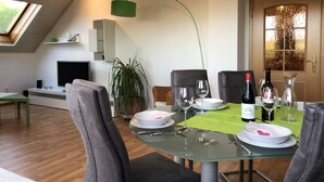 Un coin repas avec une table en verre, des chaises et une plante verte.