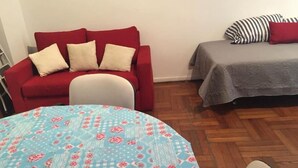 A room with a red sofa, a grey sofa, a round table with a floral tablecloth, and a patterned floor. - Incredible Rodriguez Pena (Buenos Aires)