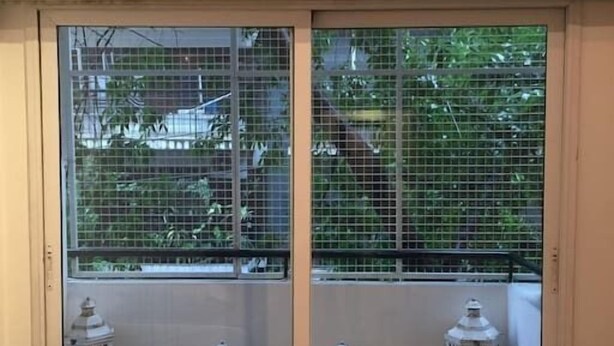 A sliding glass door with a view of a balcony, two white lanterns, and a wooden deck. - Incredible Rodriguez Pena (Buenos Aires)