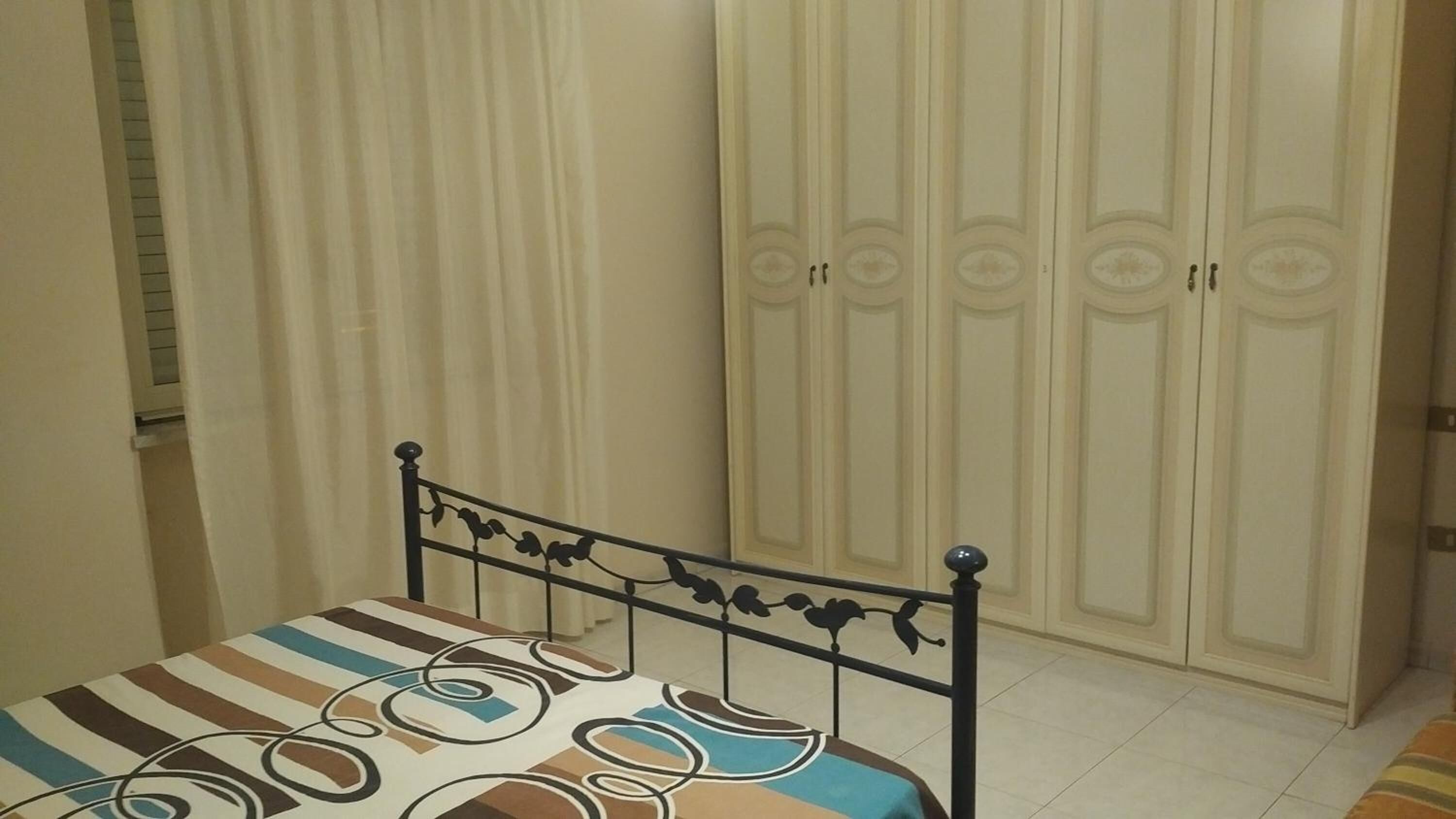 A bedroom with a bed, a wardrobe, and a window with curtains.