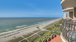 Un hotel frente a la playa con balcones con vistas al océano, una playa de arena y un cielo despejado.