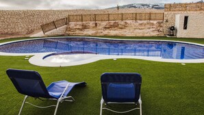 A swimming pool with two blue lawn chairs on the grass. - Ocean Gardens B3 (Naxxar)