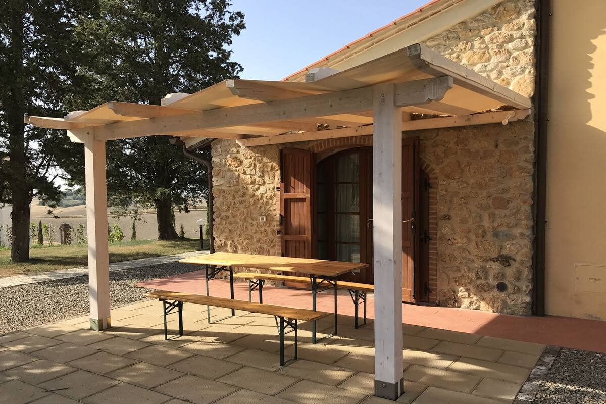 A covered outdoor seating area with a stone wall and wooden door.