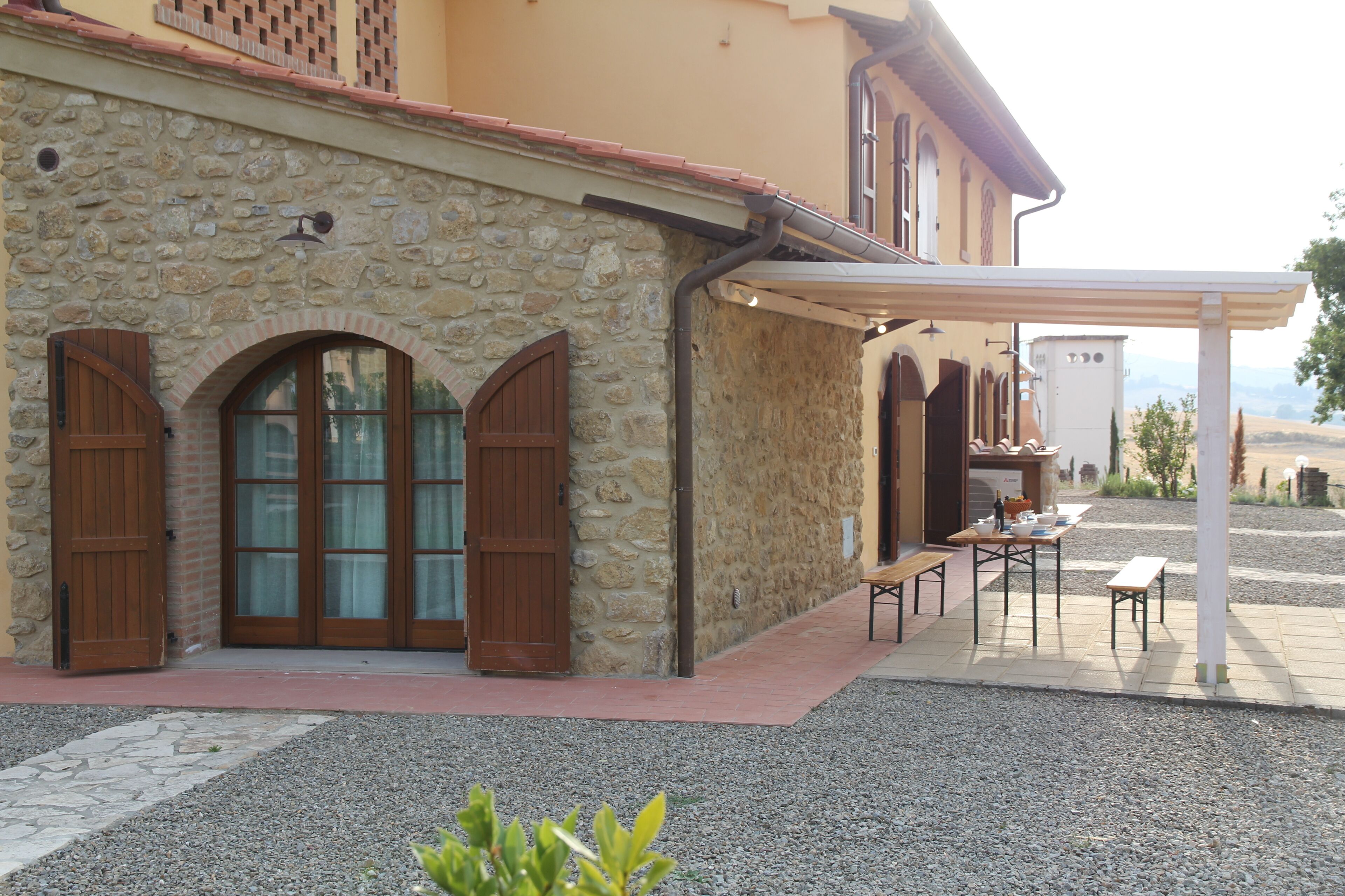 Un edificio de piedra con ventanas de arco y un área de estar cubierta al aire libre.