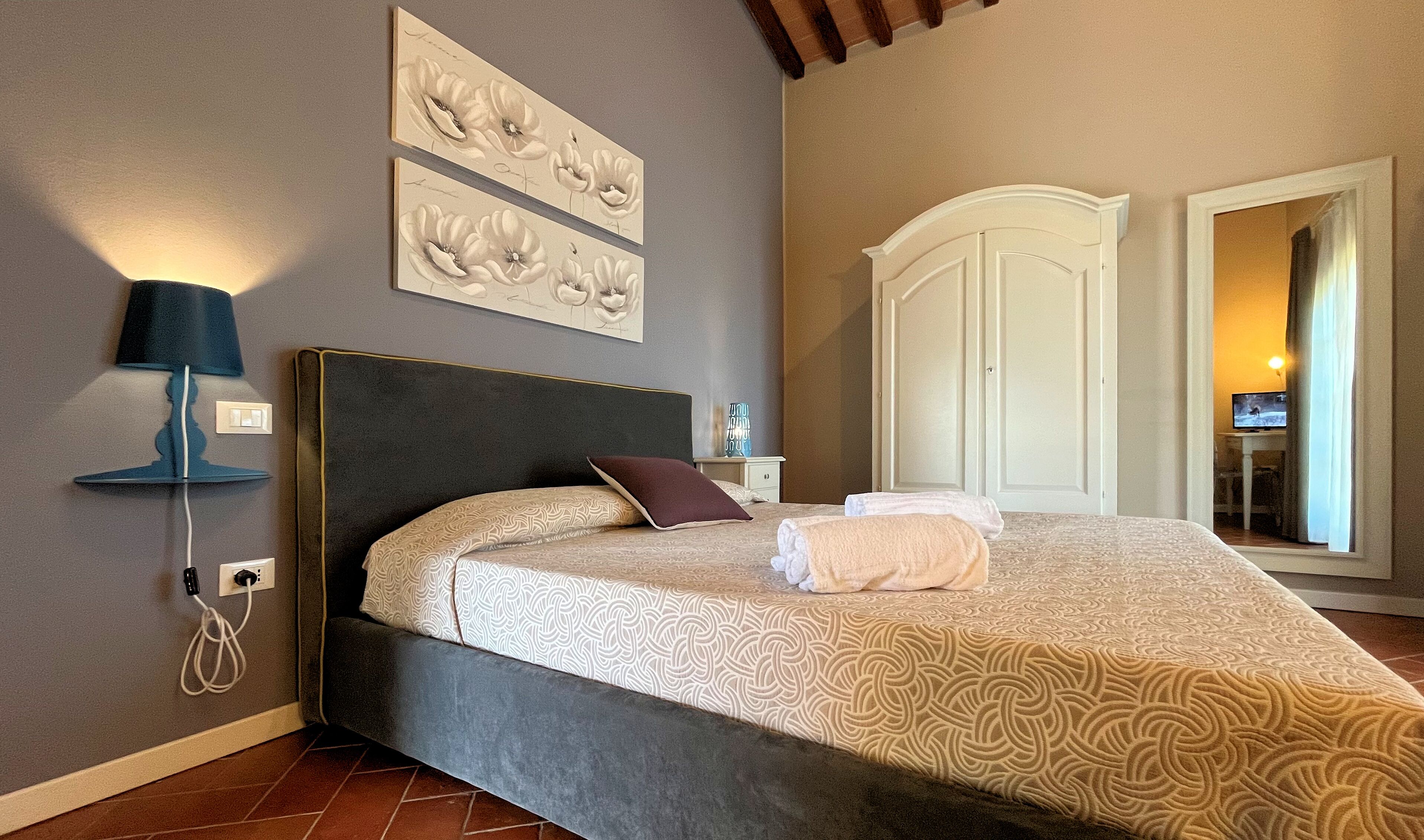 A bedroom with a bed, a nightstand, a lamp, and artwork on the wall.
