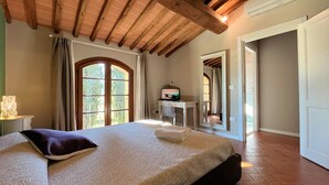 Een slaapkamer met een groot bed, een bureau met een computer en een raam met gordijnen.