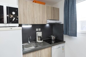 A compact kitchenette with a built-in microwave, coffee maker, stove, and dishwasher. - Terraced Houses in France with Garden (Le Chateau d'Oléron)