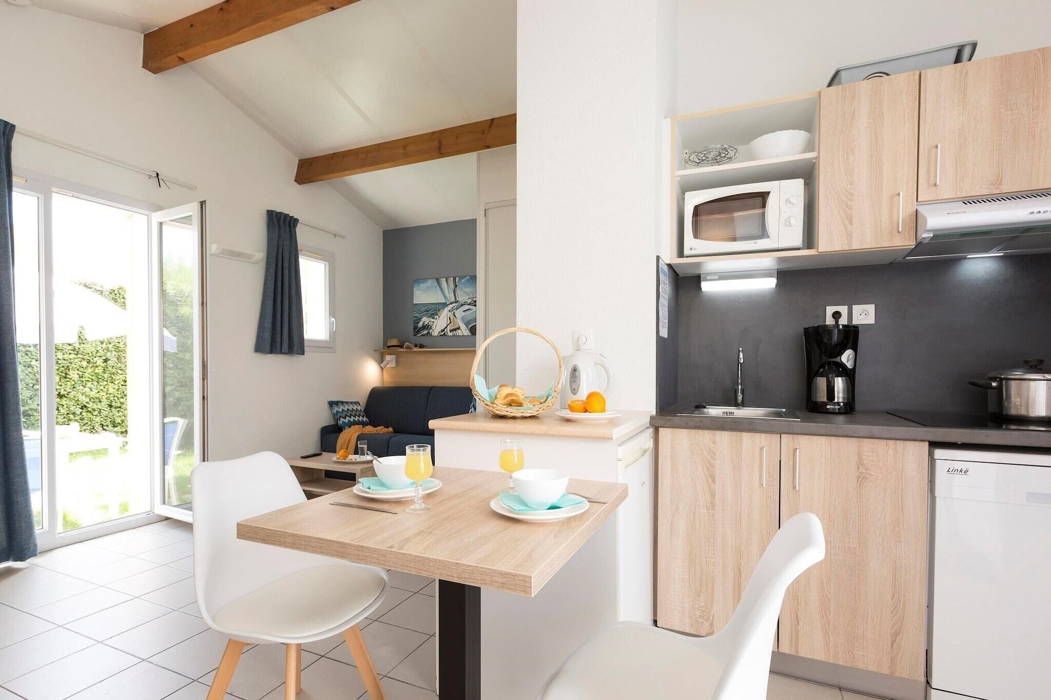 A modern kitchen with wooden cabinets, a dining table with chairs, and a view of the outdoors.