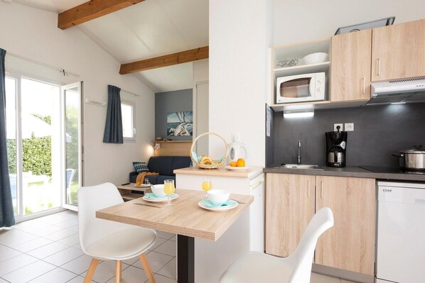 A modern kitchen with wooden cabinets, a dining table with chairs, and a view of the outdoors.