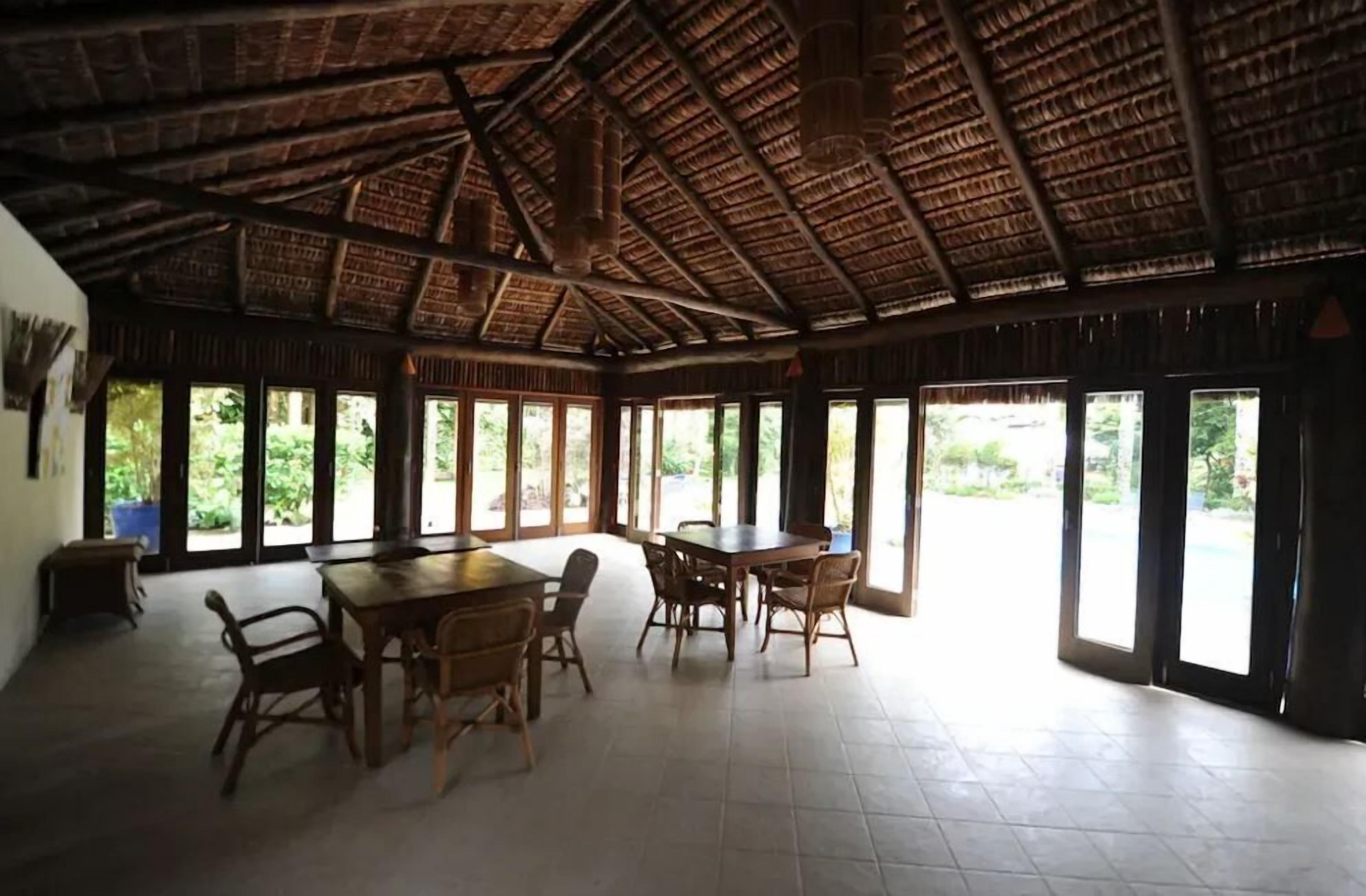 A spacious room with a high ceiling and large windows, providing ample natural light and views of the outdoors.