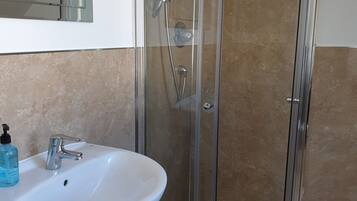 A bathroom with a glass-enclosed shower, a white sink, and a mirror above the sink.