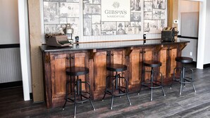 A bar area with a vintage typewriter, wooden stools, and a wall displaying historical photos. - Gibson's Warehouse (Staunton)