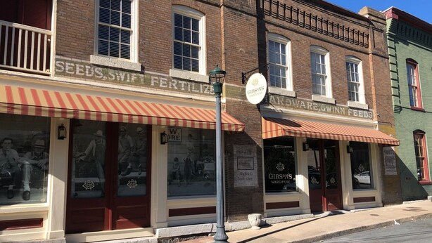 A row of brick buildings with storefronts, including a hardware store and a seed and fertilizer shop. - Gibson's Warehouse (Staunton)