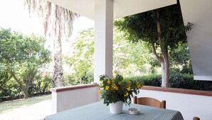 Una mesa con mantel a cuadros, una planta en maceta con flores amarillas y un tazón blanco sobre la mesa.