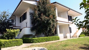 Una casa de dos pisos con balcón, escaleras y un césped bien cuidado.