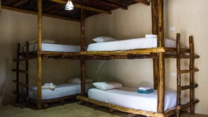A rustic room with three bunk beds made of wood, each with white bedding and pillows. - Hostal Boutique (Tulum)