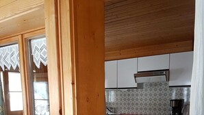 A wooden interior with a kitchen area featuring white cabinets, a stove, and a coffee maker. - Vacation apartment Helma - Holiday apartment 1 (Blons)