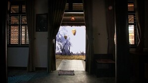 Un pasillo con un rug adornado, un banco y vistas a un paisaje con árboles y un edificio.