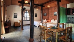 Una habitación rústica con una mesa de madera, una cama con ropa blanca y una pared de ladrillo.