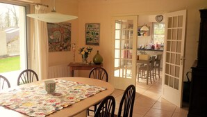 Un coin repas avec une table dressée pour quatre personnes, un vase rempli de fleurs et un tableau accroché au mur.