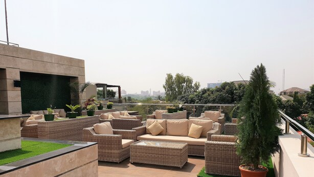 Eine Dachterrasse mit Korbmöbeln, Topfpflanzen und Blick auf die Stadtlandschaft.
