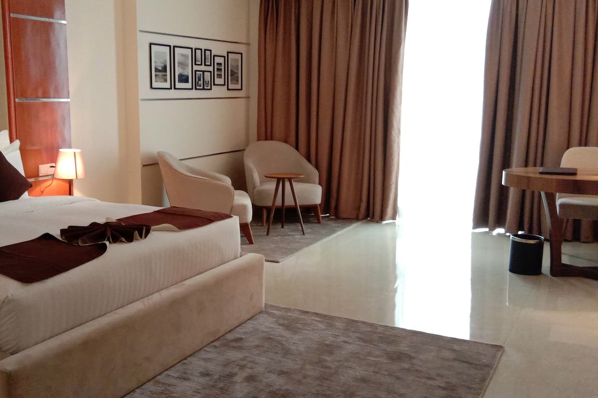 Una camera d'albergo con un letto grande, una scrivania, una sedia e una lampada.