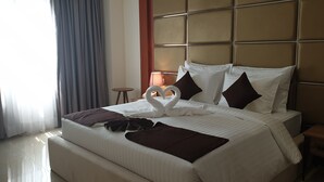 Ein Hotelzimmer mit einem großen Bett, einem Kopfteil, einem kleinen Tisch und einer Lampe.