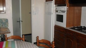 Una cocina con armarios de madera, un refrigerador blanco, un horno y una estufa a gas.