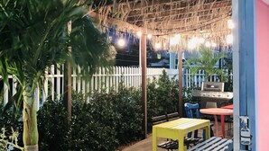 Un patio al aire libre con techo de paja, una parrilla y un conjunto de asientos.
