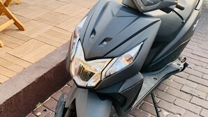 Una patineta estacionada con logotipo de Honda, asiento, manillar y faro.