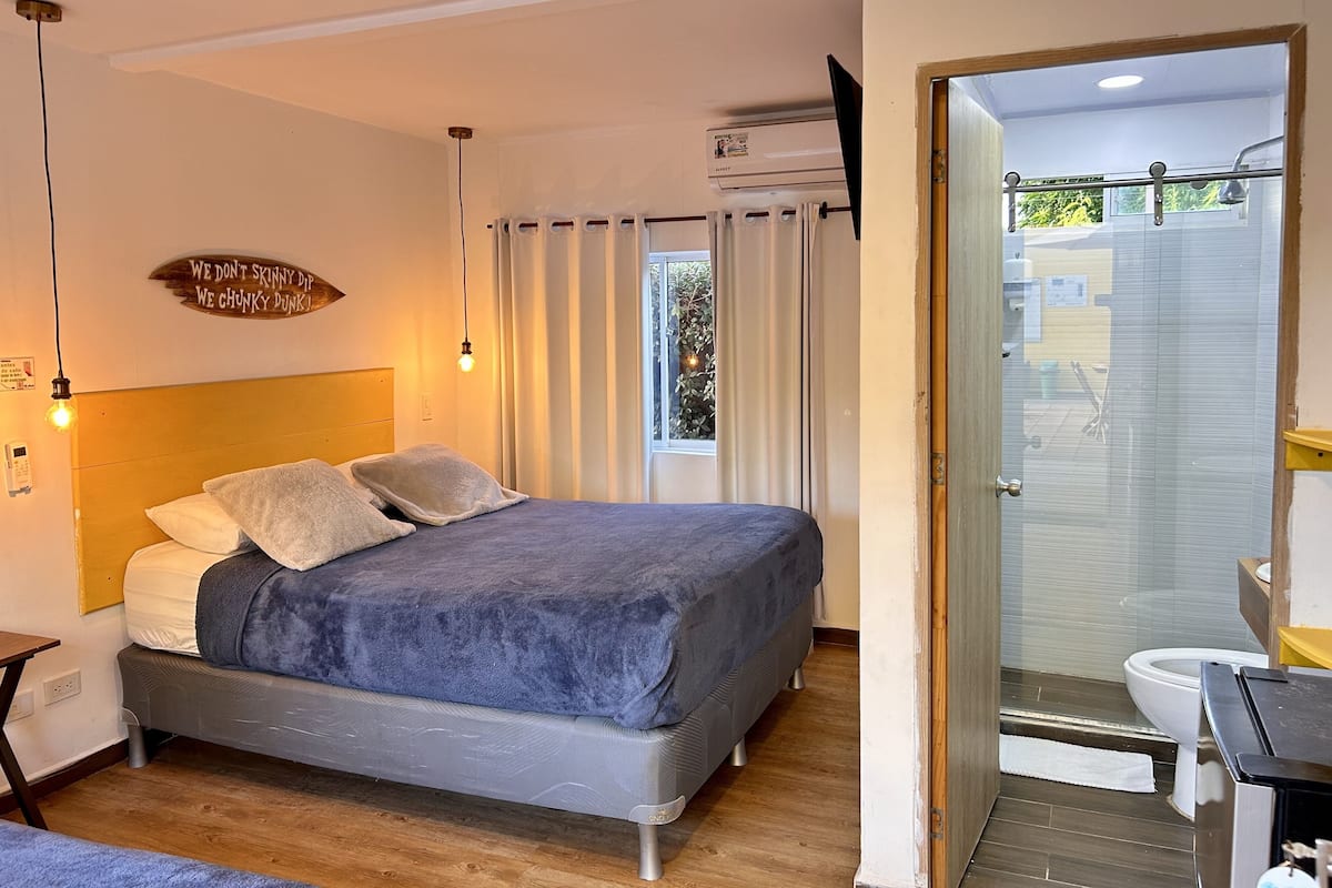 A modern bedroom with a bed, bedside table, and a window with curtains.
