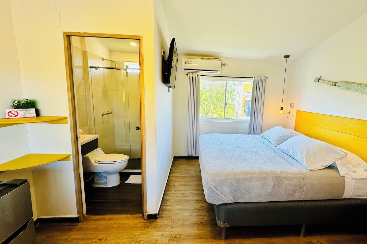 A compact bedroom with a bed, bedside table, and a window.
