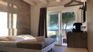 Un dormitorio con cama, una mesita de noche con cafetera y vistas al exterior a través de un ventanal corredero.