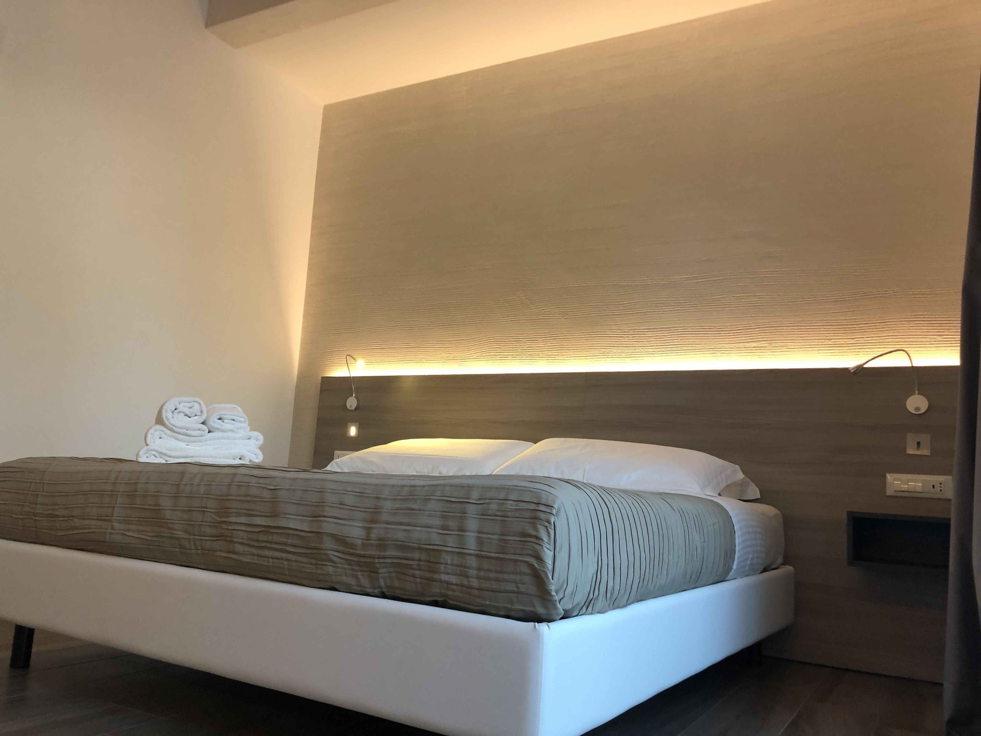 Ein modernes Schlafzimmer mit einem Bett, einer Nachttischlampe und einer Wandleuchte.