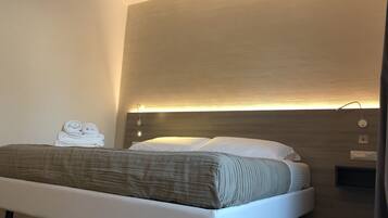 Ein modernes Schlafzimmer mit einem Bett, einer Nachttischlampe und einer Wandleuchte.