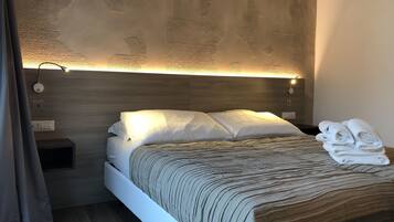 Un dormitorio moderno con cabecera de madera, una mesita de noche con lámpara y una cama bien tendida con manta a rayas.