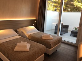 A hotel room with two beds, a sliding glass door leading to an outdoor seating area.