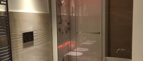 A modern bathroom with a glass-enclosed shower, a toilet, and a sink.