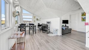 Ein geräumiger Lofts mit hohen Decken, großen Fenstern, einem Essbereich mit Tisch und Stühlen, einer Couch und einem Fernseher.