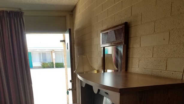 Una habitación con un armario de madera, un televisor y una ventana con cortinas.