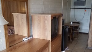 Una habitación compacta con un escritorio de madera, televisión, una mesita y una silla.