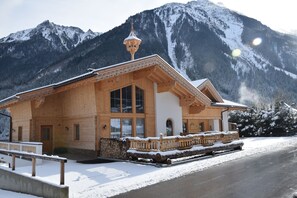Un bâtiment en bois doté d’un balcon et d’un toit enneigé, se dressant sur un fond de montagnes.