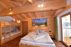 Une cabane en bois avec des lits superposés, un grand lit et un tableau représentant un paysage accroché au mur.