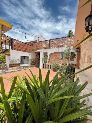 A courtyard with a brick wall, potted plants, and a staircase. - Santa Josefita (San Pedro Cholula)