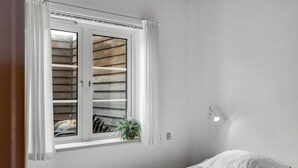 Ein Schlafzimmer mit Fenster, Nachttisch, Lampe und Bett.