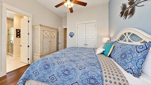 A bedroom with a bed, a ceiling fan, and a door leading to a bathroom.