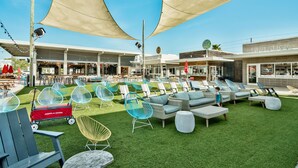 An outdoor seating area with various chairs and a dining table, surrounded by buildings with shops and a sign that reads "LUB SHOP". - "Holiday House" 3BR/2.5 Bath at Prominence (Santa Rosa Beach)