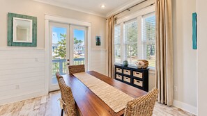 A dining area with a wooden table, wicker chairs, a woven rug, and a black console with baskets.